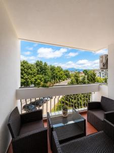 a balcony with two chairs and a glass table at Riverside Apartment, 10min Airport in Sarajevo