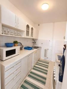 a kitchen with white cabinets and a green and white rug at Riverside Apartment, 10min Airport in Sarajevo