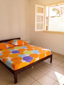 a bed with a colorful comforter in a bedroom at Maison accueillante à Anse-Bertrand avec jardin privé 70 m² in Anse-Bertrand