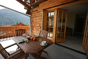 a wooden table on the balcony of a house at Appartement spacieux à Châtel 120 m² avec terrasse privée in Châtel