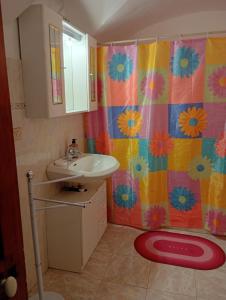 a bathroom with a sink and a colorful shower curtain at Casa Arancia in Isolabona +24 photos