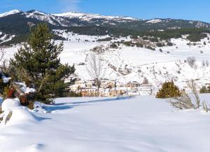 a snow covered hill with a village in the distance at Appartement charmant avec vue sur lac et montagne – 75 m² in Fontrabiouse
