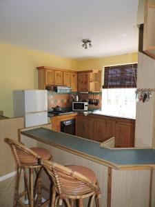 a kitchen with wooden cabinets and a counter with two chairs at Charming villa in Blue Bay with private pool in Blue Bay