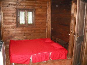 a red bed in a wooden room with a window at Comfortable Chalet in Giarola with Mountain View in Busana