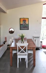 a dining room with a wooden table and white chairs at Cozy House in Seia with Fireplace in Faia