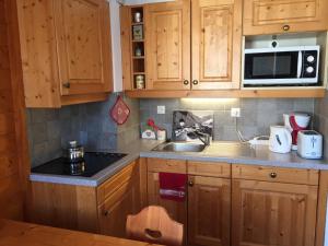 a kitchen with wooden cabinets and a sink and a microwave at Studio charmant à Valloire - 21m² - Vue sur montagne in Valloire
