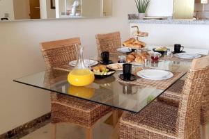 a glass table with a bowl of orange juice at Spacious apartment in La Cala de Mijas with sea view. in La Cala de Mijas
