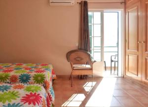 a bedroom with a bed and a chair and a window at Charming house in Vila Nova de Cacela with garden in Vila Nova De Cacela