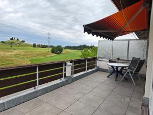 ein Balkon mit einem Tisch und Blick auf ein Feld in der Unterkunft Auszeit mit Sauna und Pool in Scheidegg