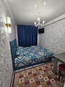 a bedroom with a blue bed and a table at Престиж 2 номер in Shymkent