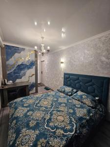 a bedroom with a blue bed and a painting on the wall at Престиж 2 номер in Shymkent