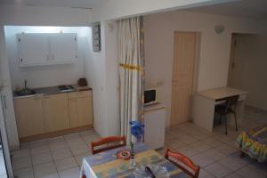 a small kitchen with a table and a table and chairs at Studio cosy au Moule 30 m² avec jardin privé in Le Moule