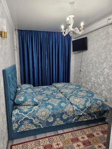 a bedroom with a blue bed and a chandelier at Престиж 2 номер in Shymkent