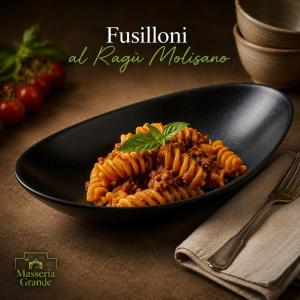 a black plate of pasta on a table with a fork at Masseria Grande Hotel - Ristorante in Montecilfone