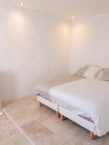 a white bed in a room with a tile floor at Appartement spacieux à Algajola in Algajola