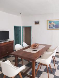 a dining room with a wooden table and white chairs at Appartement spacieux à Algajola in Algajola