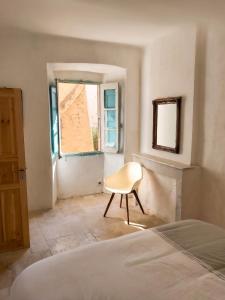 a bedroom with a chair in front of a window at Appartement spacieux à Algajola in Algajola +8 photos