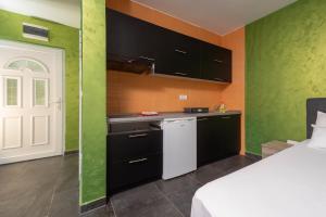 a kitchen with black cabinets and a white refrigerator at Alessandra Apartments & free private parking in Sveti Stefan