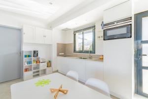a white kitchen with a white table and chairs at Appartement charmant, Malaucène, 52 m², piscine partagée in Malaucène