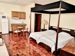 a bedroom with a canopy bed and a kitchen at Charming studio in Funchal, 30m², city view in Funchal