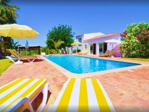 a swimming pool with two lounge chairs and an umbrella at Elegant villa with sea view in Loulé + private pool in Loulé