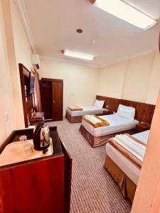 a hotel room with two beds and a table at فندق جوهرة ذاخر رويال توصيل مجاني للحرم - Jewel Thakher Royal Hotel Free Shuttle to Haram in Mecca