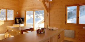 a log cabin kitchen with a table and windows at Chalet accueillant avec vue sur la montagne - 180 m² - Valmorel in Les Avanchers