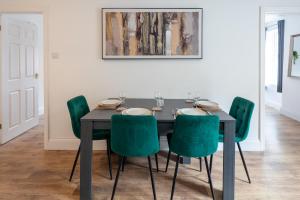 a dining room with a black table and green chairs at Spacious 2BR APT - Sleeps 5 - Private Parking in Highbridge