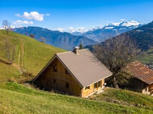a barn on a hill with mountains in the background at Chalet accueillant avec vue sur la montagne - 180 m² - Valmorel in Les Avanchers