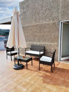 a patio with three chairs and a white umbrella at Apartment with Mountain View in Eiriz – 65 sqm – Terrace in Eiriz