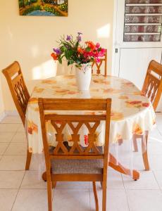 a dining room table with a vase of flowers on it at Appartement douillet avec vue sur les montagnes au Vauclin in Le Vauclin