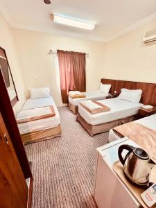 a hotel room with two beds and a kitchen at فندق جوهرة ذاخر رويال توصيل مجاني للحرم - Jewel Thakher Royal Hotel Free Shuttle to Haram in Mecca