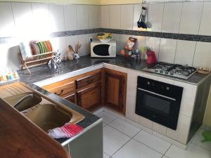 a kitchen with a sink and a stove and a microwave at Appartement avec vue sur la mer à Le Marin, Climatisé, 80 m² in Le Marin