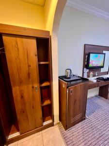 a room with a desk and a cabinet with a television at فندق جوهرة ذاخر رويال توصيل مجاني للحرم - Jewel Thakher Royal Hotel Free Shuttle to Haram in Mecca