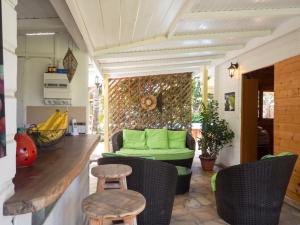 a porch with a green couch and chairs at Chalet confortable au Vauclin avec piscine privée in Le Vauclin
