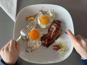 a plate of breakfast food with eggs and bacon at Pótkerék Motel in Győr +6 photos