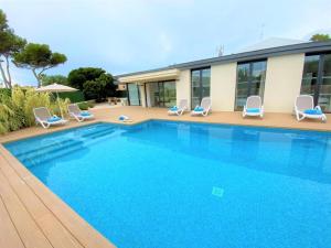 a swimming pool with chairs and a house at Villa LUCIA in Cala en Blanes