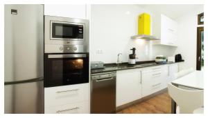 a kitchen with white cabinets and a stainless steel refrigerator at Elegant Villa in Outes with Pool in Serantes