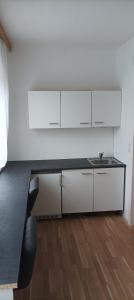 a kitchen with white cabinets and a black counter top at Zimmer zum Viadukt in Neulengbach
