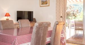 a dining room with a table and chairs and a television at Appartement confortable à Oderen 68 m² avec piscine partagée in Oderen