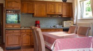 a kitchen with wooden cabinets and a table with a table cloth at Appartement confortable à Oderen 68 m² avec piscine partagée in Oderen +14 photos