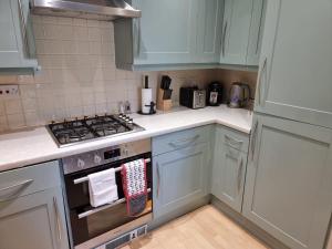 a kitchen with white cabinets and a stove top oven at Hunters Wharf River View by Select SA in Reading