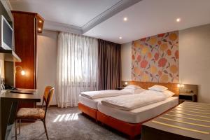 ein Hotelzimmer mit einem Bett, einem Schreibtisch und einem Tisch in der Unterkunft Hotel Im Engel in Warendorf