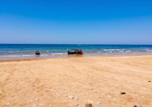 a sandy beach with two boats in the ocean at Charming Apartment in Imi Ouaddar in Agadir nʼ Aït Sa
