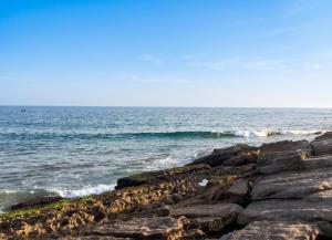 a view of the ocean from a rocky beach at Charming Apartment in Imi Ouaddar in Agadir nʼ Aït Sa +4 photos