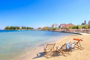 two chairs and a table on a beach at Adriatic Oasis Apartments in Preko