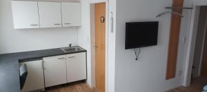 a kitchen with a sink and a tv on a wall at Zimmer zum Viadukt in Neulengbach +13 photos