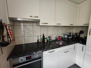 a kitchen with white cabinets and black counter tops at Grosses Doppelzimmer in Privathaus in Flums
