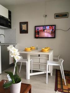 a white dining room table with a tv on the wall at Appartement cosy avec piscine partagée - Guérande - 30 m² in Guérande