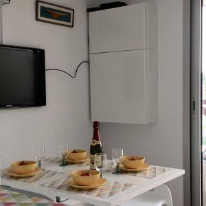 a dining room table with a television and a white table with glasses at Appartement cosy avec piscine partagée - Guérande - 30 m² in Guérande